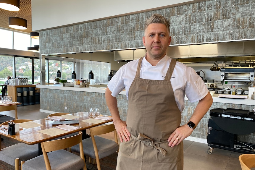 A man in a chef's apron stands in a restaurant