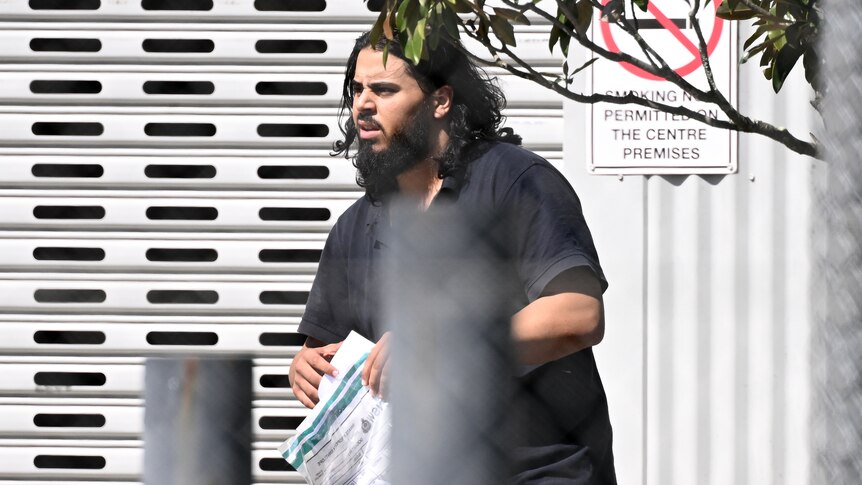 A man with long hair and a beard carrying a plastic bag