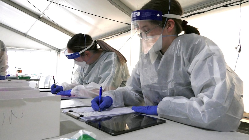 Two health workers in protective gear.