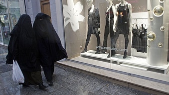 Women wearing burkas walk past clothing stores in France. (Jean-Paul Pelissier/Reuters)