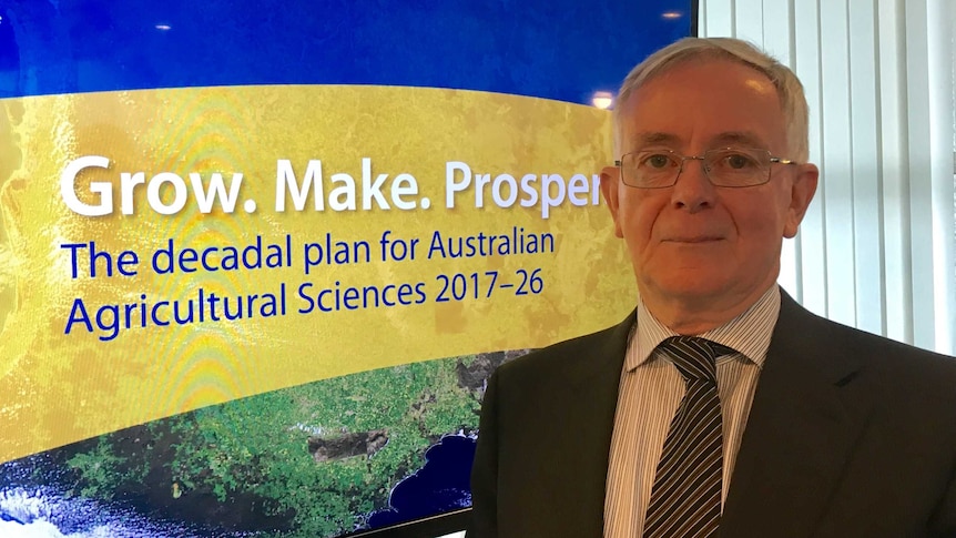 Dr Jeremy Burdon stands in front of signage reading: 'Grow. Make. Prosper: decadal plan for Australian agricultural sciences'