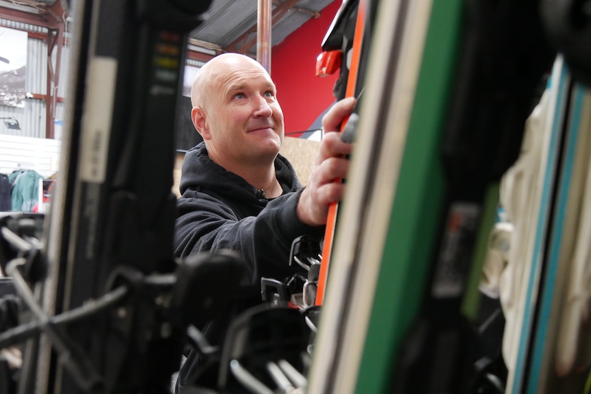 a man reaches for skis in a shop