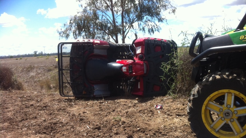 An overturned quad bike on farmland.