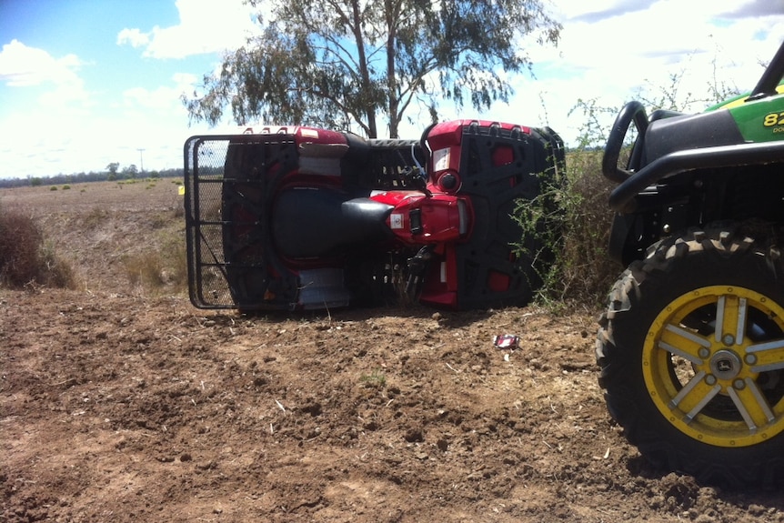 A quad bike lying on its side in a paddock.