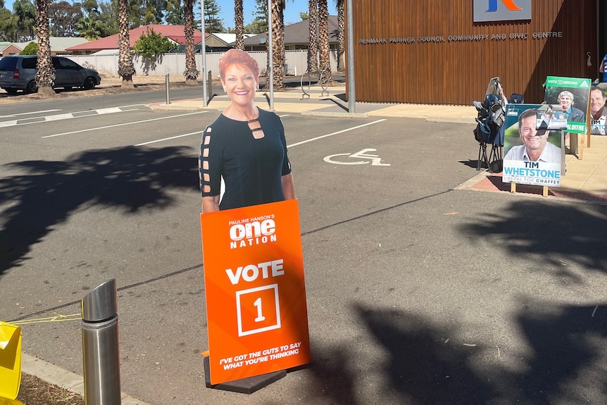 A cardboard cut-out of Pauline Hanson, a woman with red hair, outside a community centre.