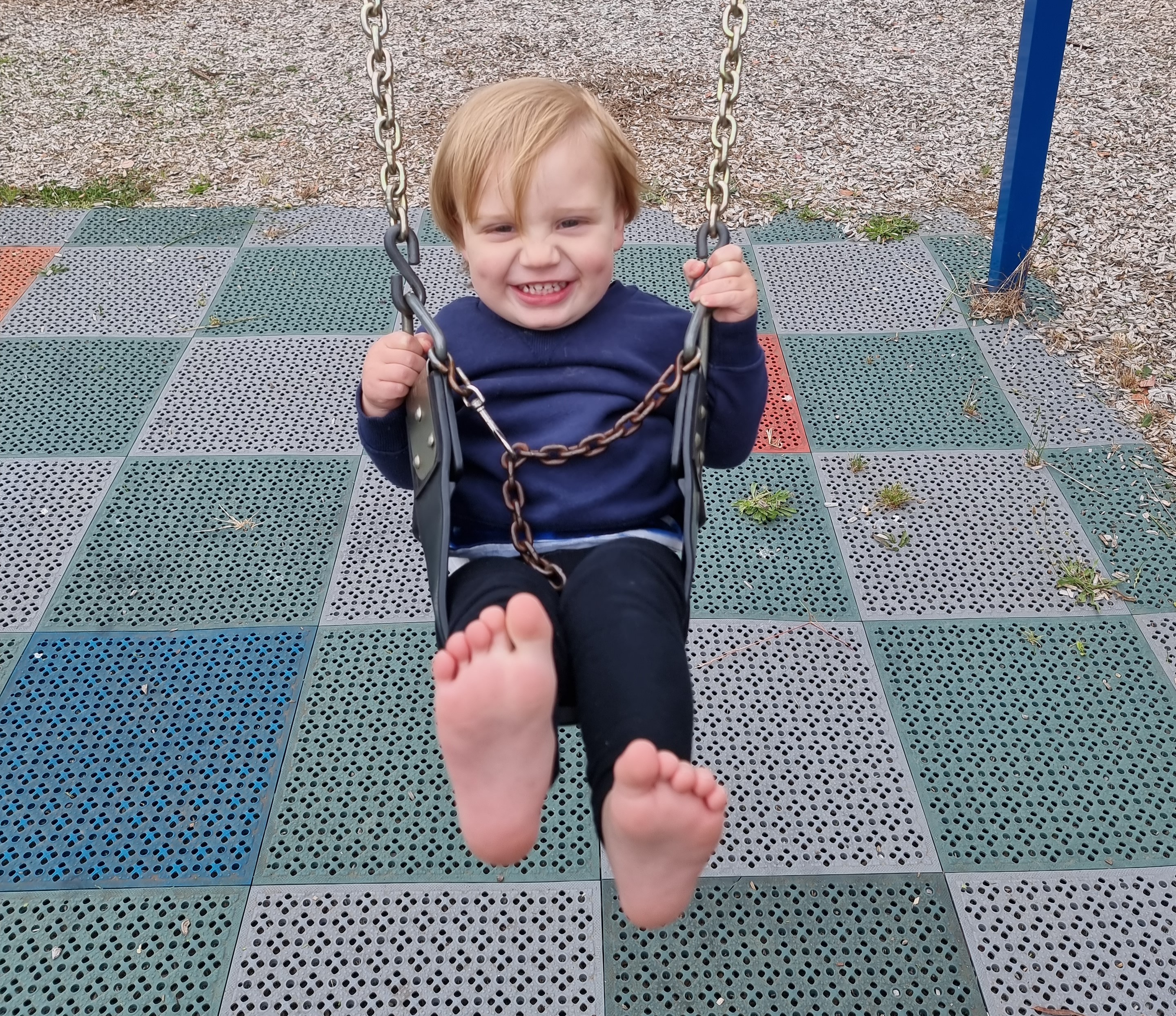 Noah Souvatzis on a playground swing 