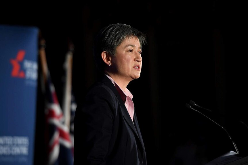 Penny Wong on stage with an Australian flag in background.