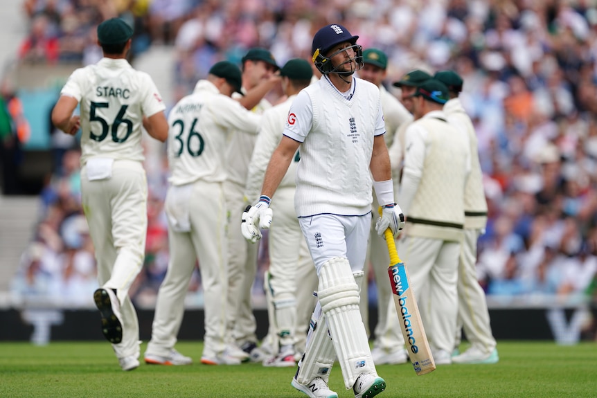 Joe Root looks disappointed as he walks off while Australia celebrates the wicket in the background