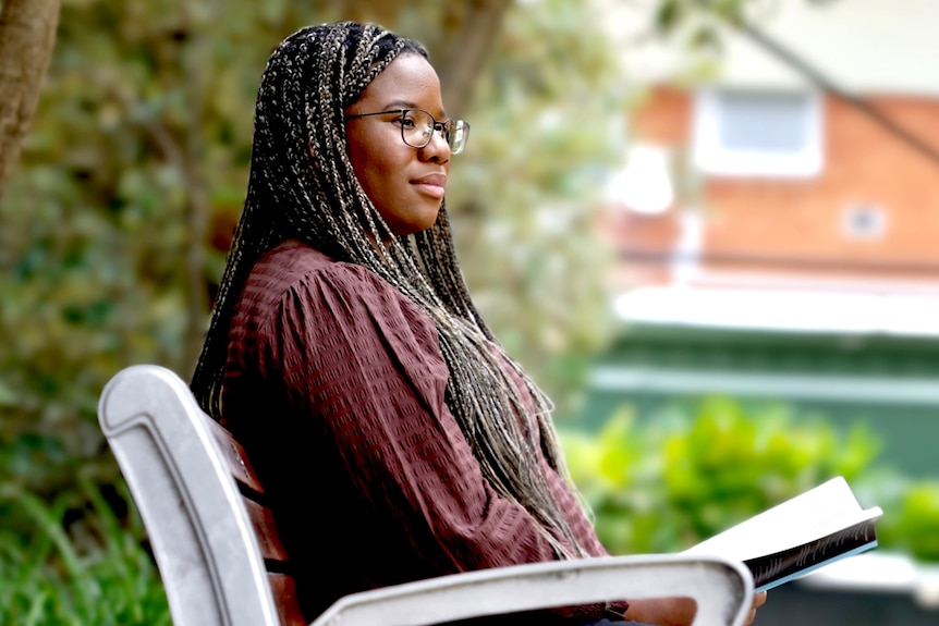 An African Australian woman sits in a park.