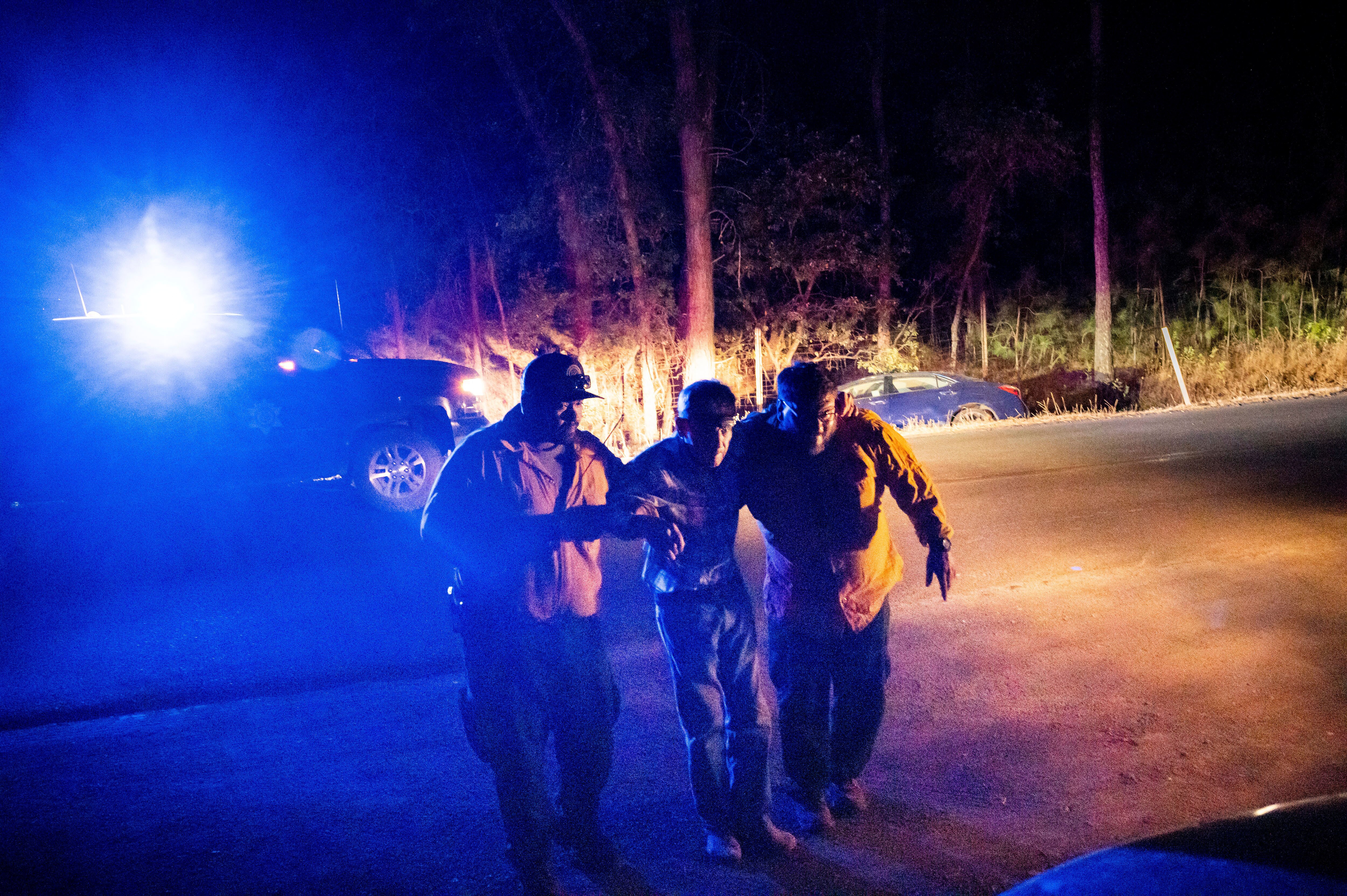 Firefighters help an elderly man from the wreck of his car