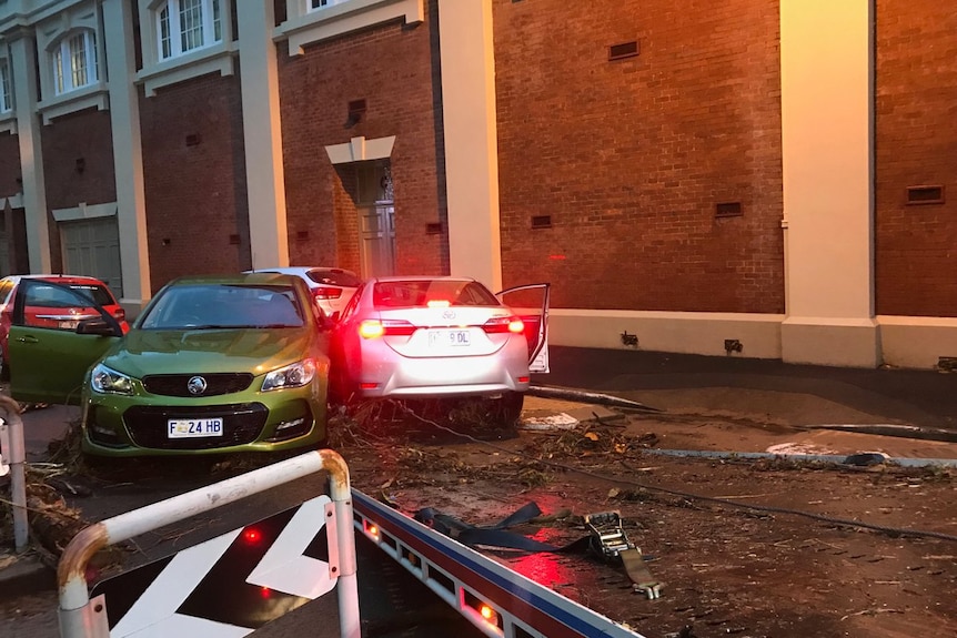 Cars swept away by floods are clustered together on a city street.