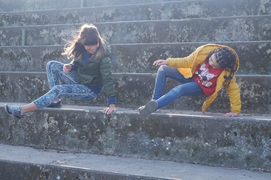 Amy Han coaches a younger girl to do parkour on some concrete steps