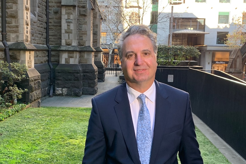 A man in a suit poses for a photo in Melbourne CBD