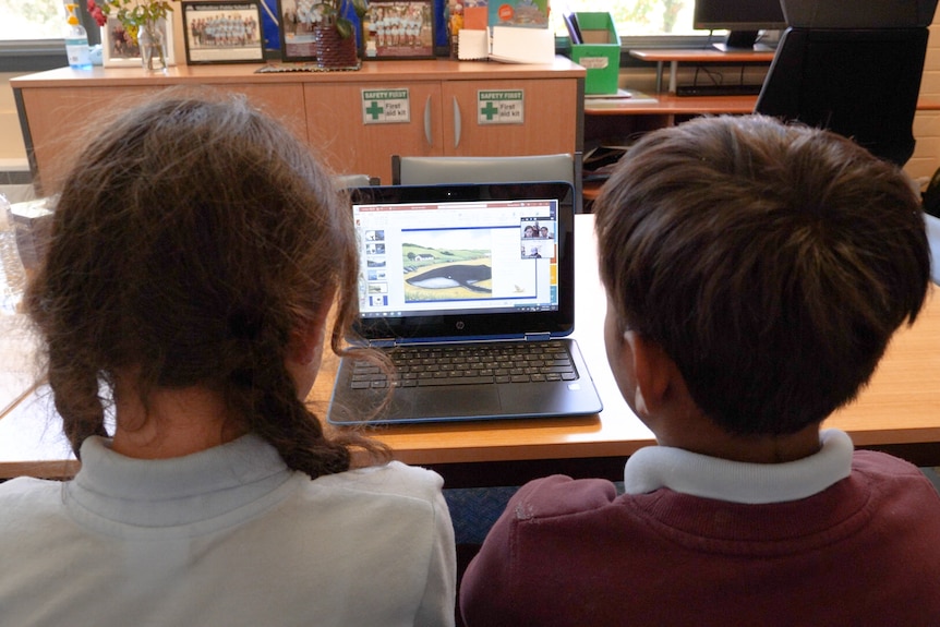 A boy and a girl sitting in front of a laptop