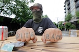 A protester displays his "bite back" tattoos as he stands guard at Seattle's Capitol Hill Occupied Protest zone.