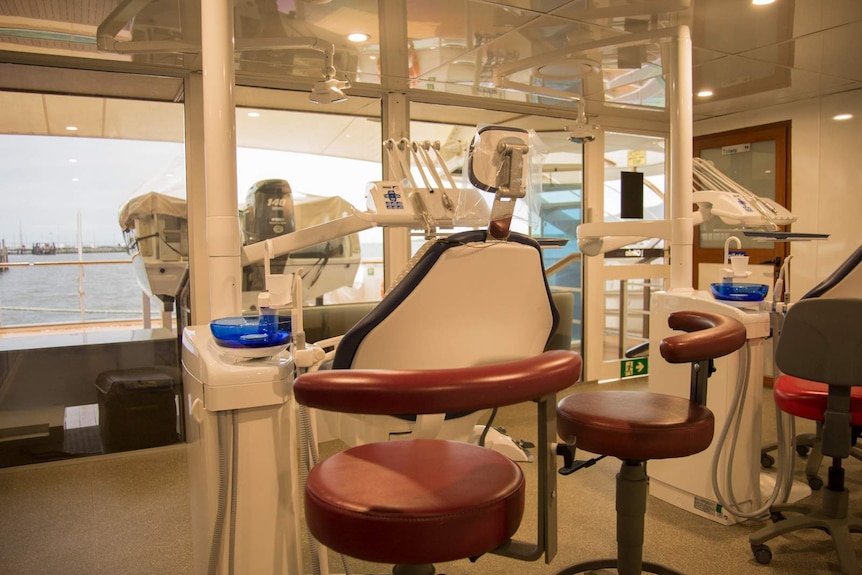 A small, glass walled room with two dental chairs and dentistry equipment at aft of the ships lowest level.