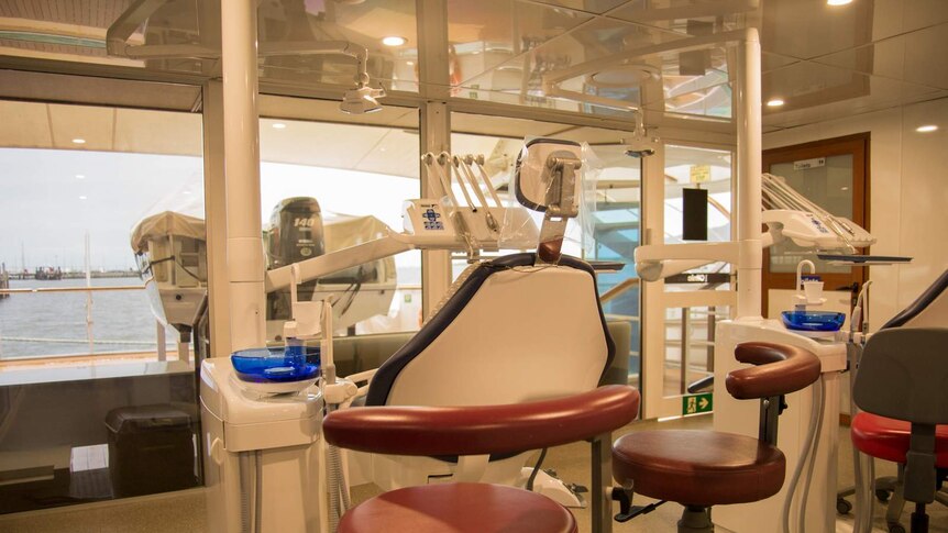 A small, glass walled room with two dental chairs and dentistry equipment at aft of the ships lowest level.