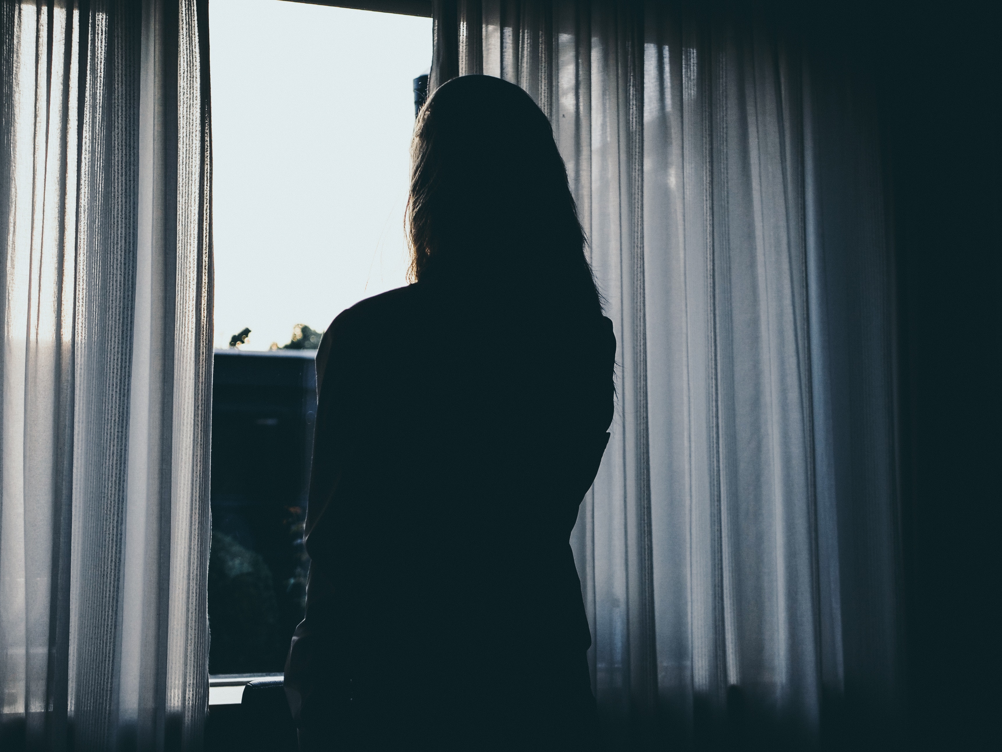 A stock image of a woman's silhouette looking out a window