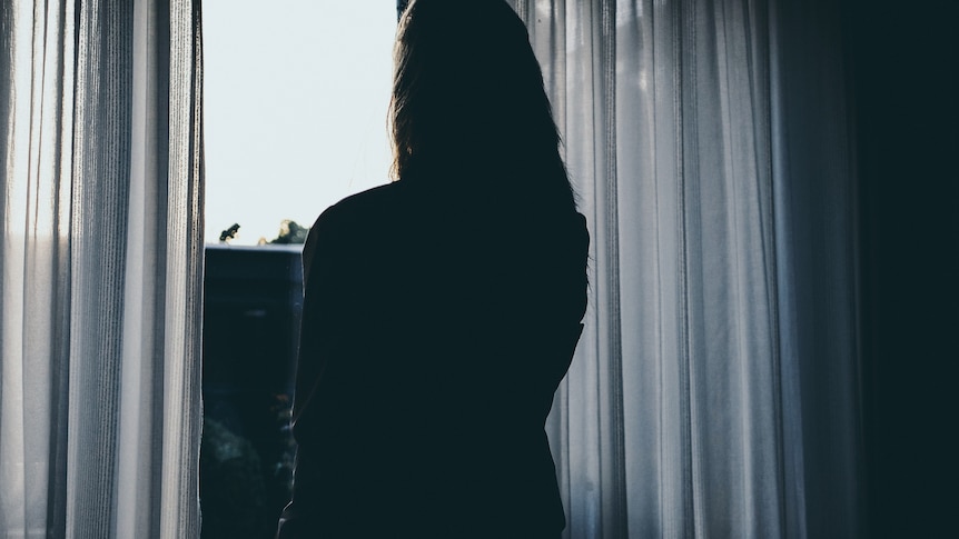 A stock image of a woman's silhouette looking out a window