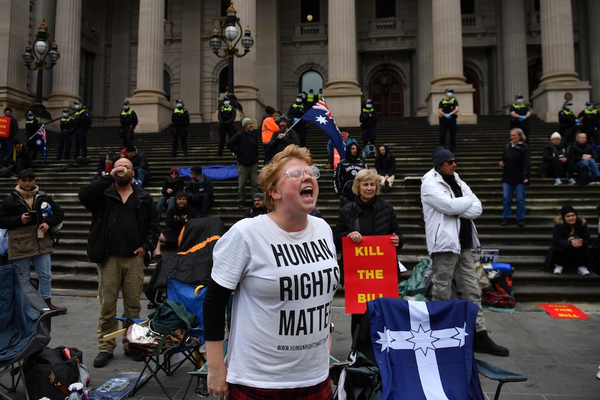 A woman wearing a tshirt that says "human rights matter" yells during a protest outside Victorian Parliament.
