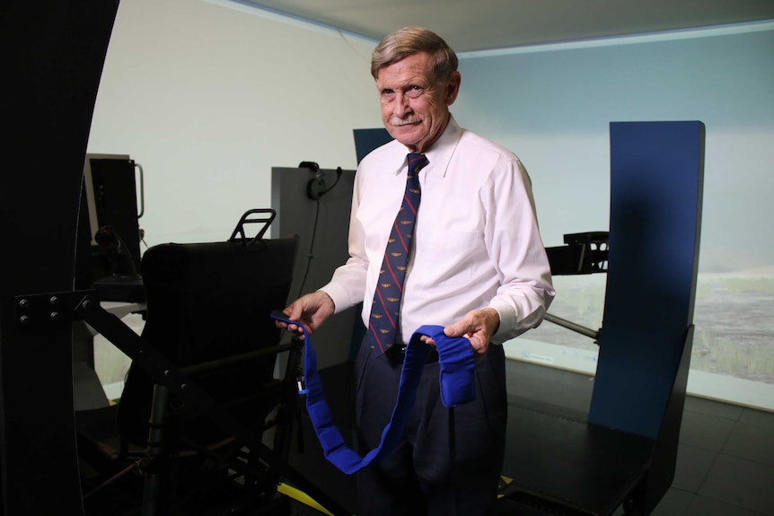 Angus Rupert poses with a belt and harness that can help pilots with spatial disorientation.