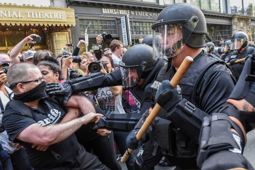 Riot police push back counter-protesters, one wearing an Antifa shirt, in Boston.