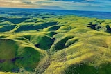 an aerial shot of rolling green hills