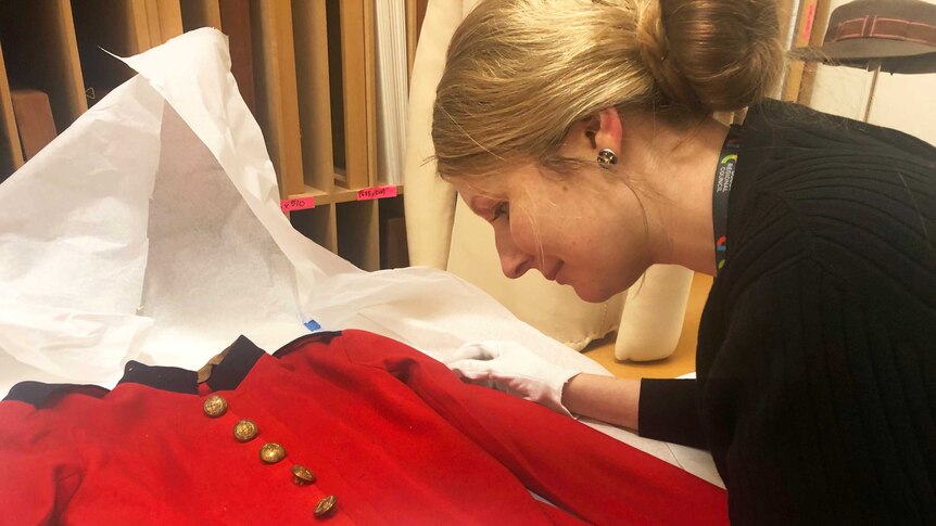 Simone Taylor inspects the military tunic with white gloves on.