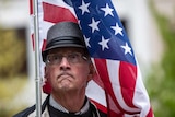 A man in a hat wrapped in an American flag makes an exaggerated pout