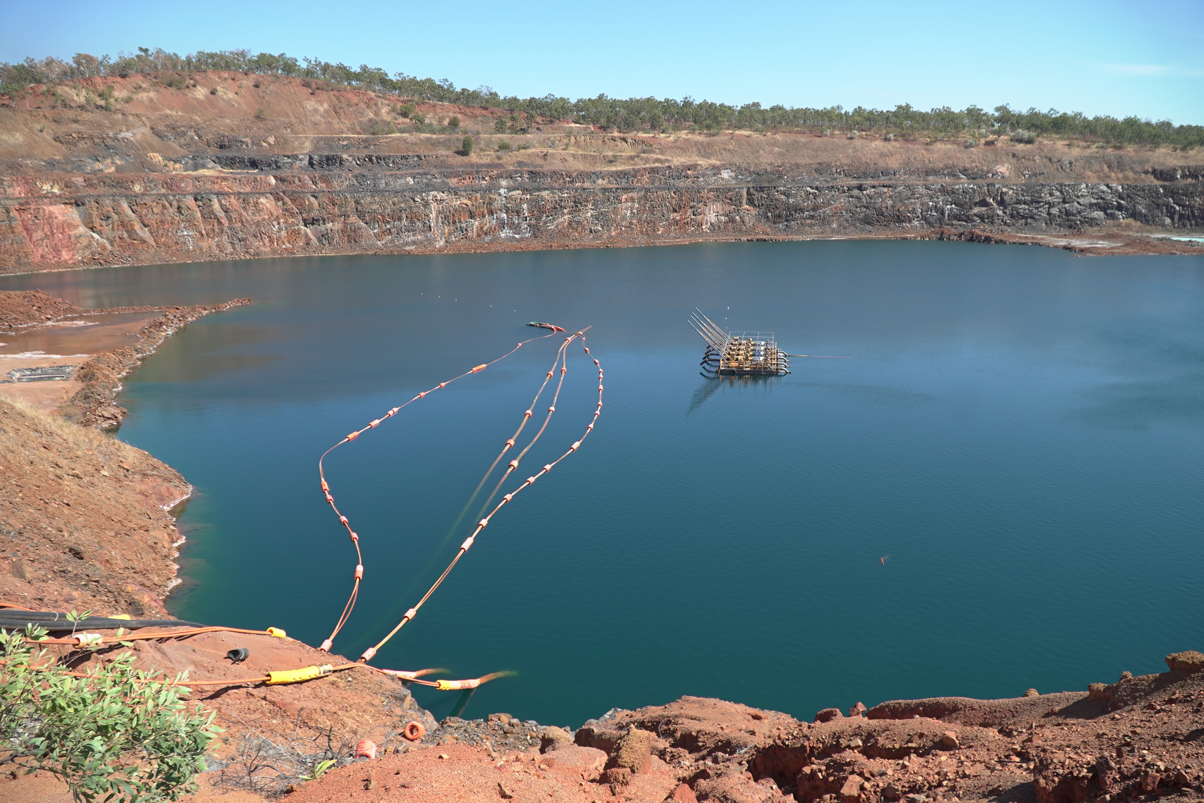 An open-cut mining pit mostly full of blue water.