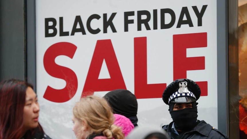 Chicago Police officers stand watch outside a store as shoppers pass by during a protest on Black Friday