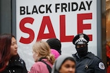 Chicago Police officers stand watch outside a store as shoppers pass by during a protest on Black Friday