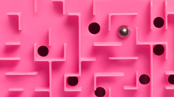 Pink plastic toy maze with holes and ball bearings to manipulate