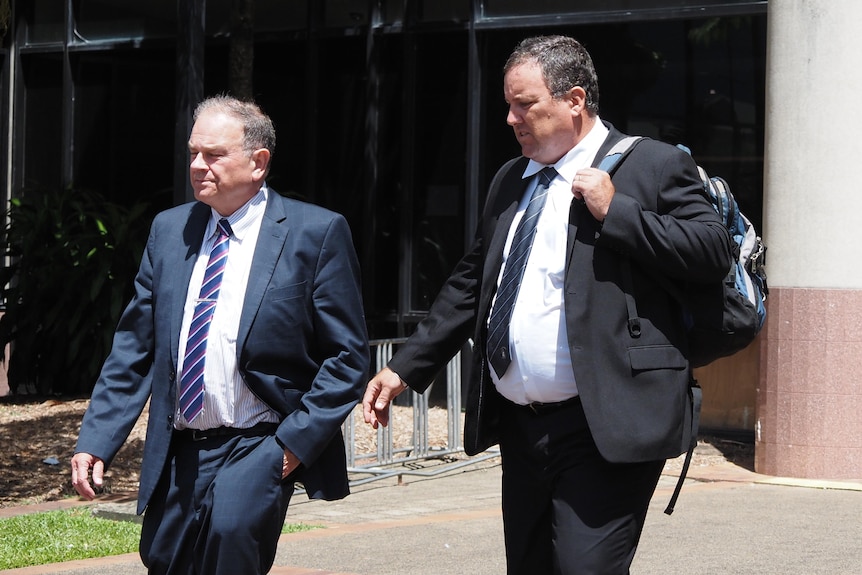 Two men in suits walk outside a Cairns courthous