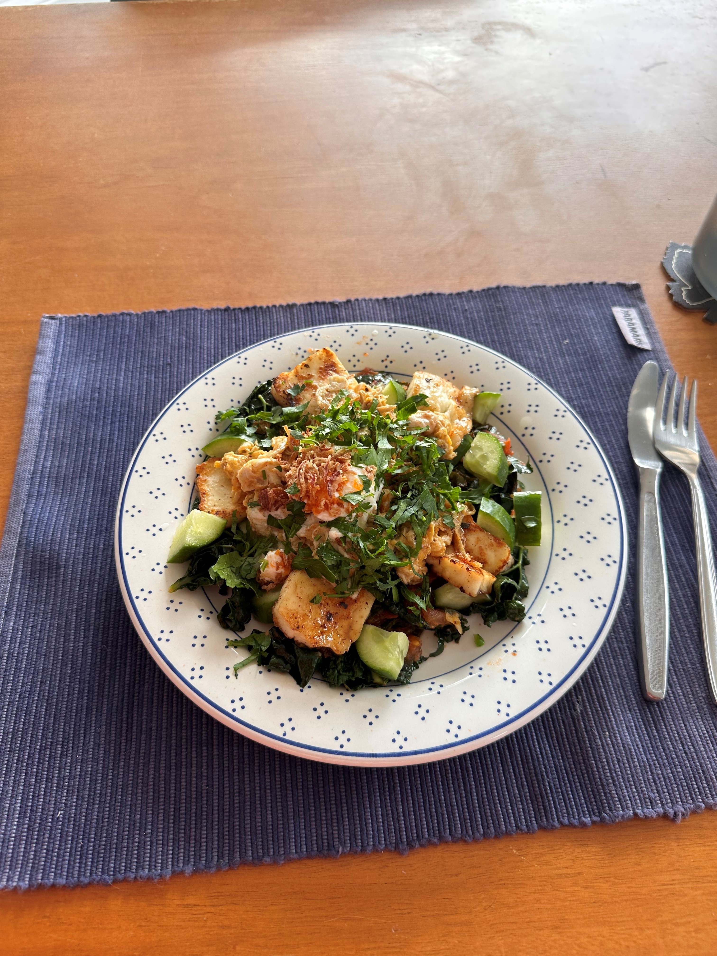 A plate on a dining table placement with a green and colourful breakfast.