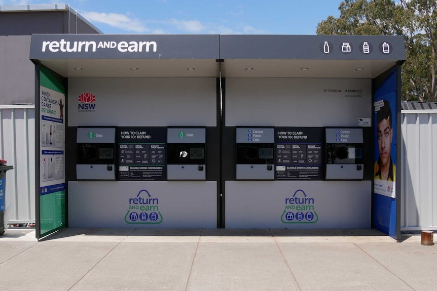 A Return and Earn point in a shopping centre carpark. There are four slots to deposit cans and bottles.