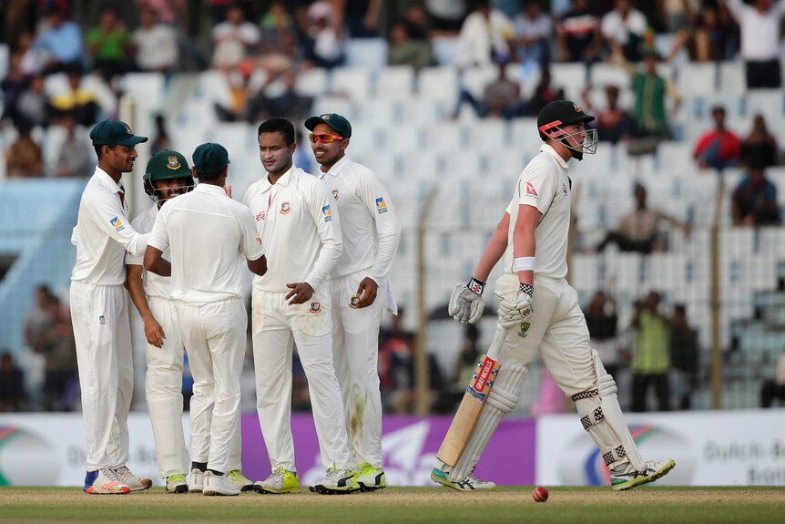 Matthew Renshaw walks off the field with Bangladesh celebrating his dismissal in the background.