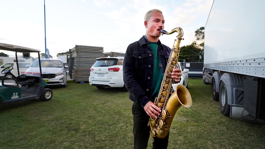 Ocean Alley's saxophone player warms up backstage in the carpark.