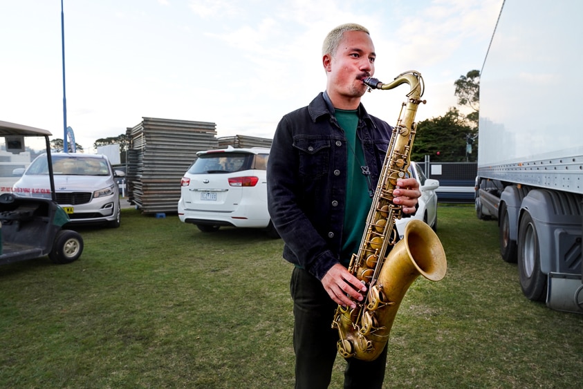 Ocean Alley's saxophone player warms up backstage in the carpark.