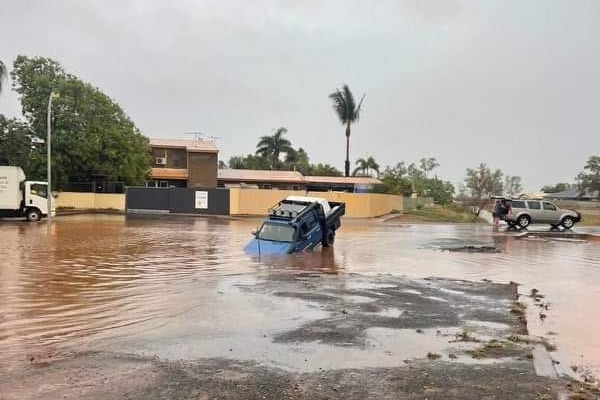 A car half submerged in murky floodwaters