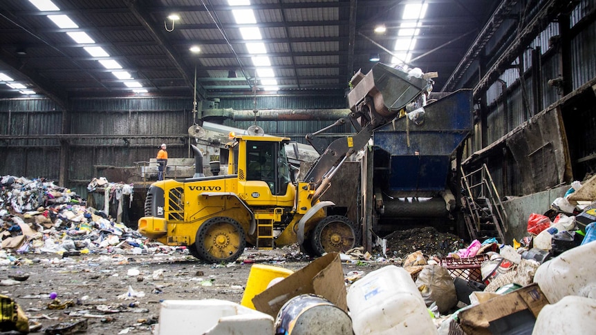 A front-end loader tips rubbish into a funnel.