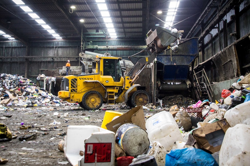 A front-end loader tips rubbish into a funnel.