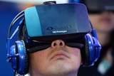 An attendee wears an Oculus Rift HD virtual reality head-mounted display as he plays a game.