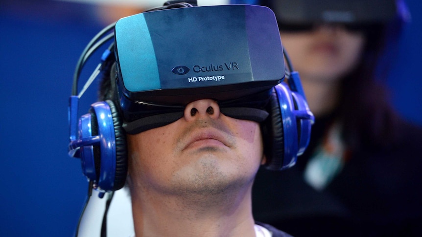 An attendee wears an Oculus Rift HD virtual reality head-mounted display as he plays a game.