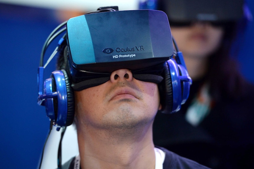 An attendee wears an Oculus Rift HD virtual reality head-mounted display as he plays a game.