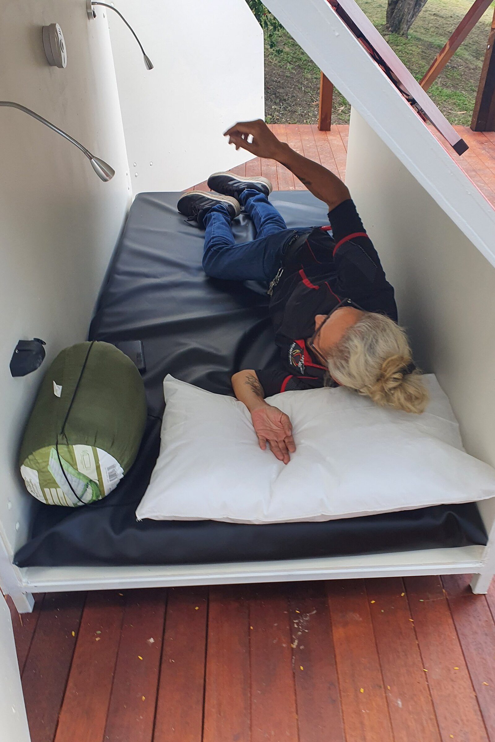 Lady laying on a bed inside a small pod with a sleeping bag.