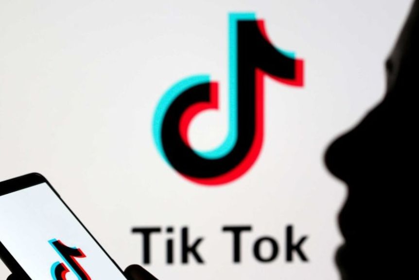 The logo for popular video social media sharing app TikTok on screen and on a phone.