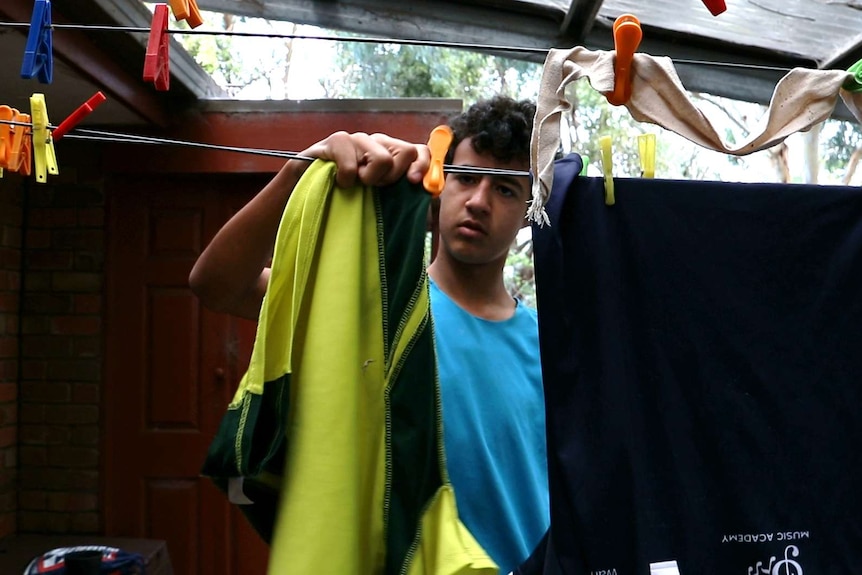 Teenage boy pegs washing on the clothesline