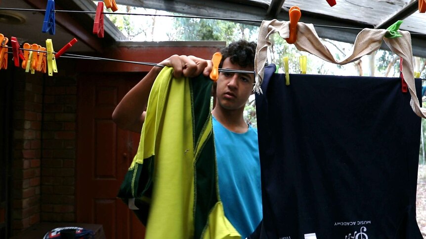Teenage boy pegs washing on the clothesline