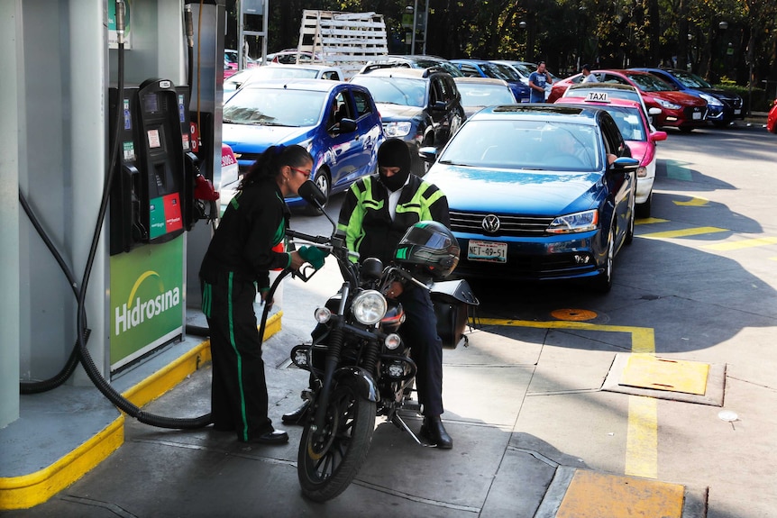 Vehicles stand in line to fill up their fuel tanks at a gas station in Mexico.
